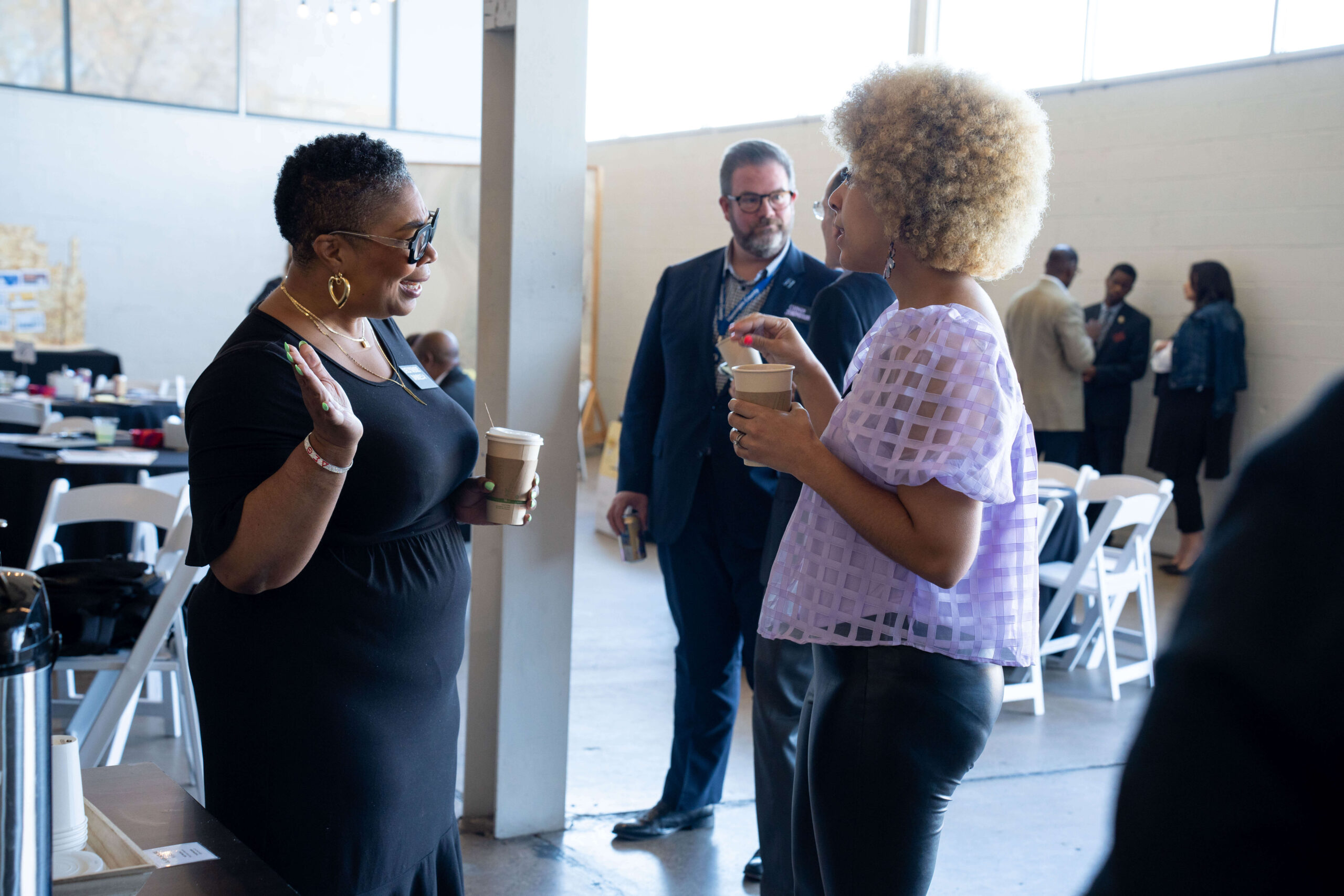 Two individuals engaged in discussion while holding coffee