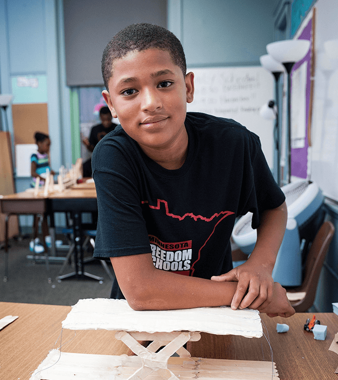 A young boy attentively works on a hands-on project in a classroom setting.